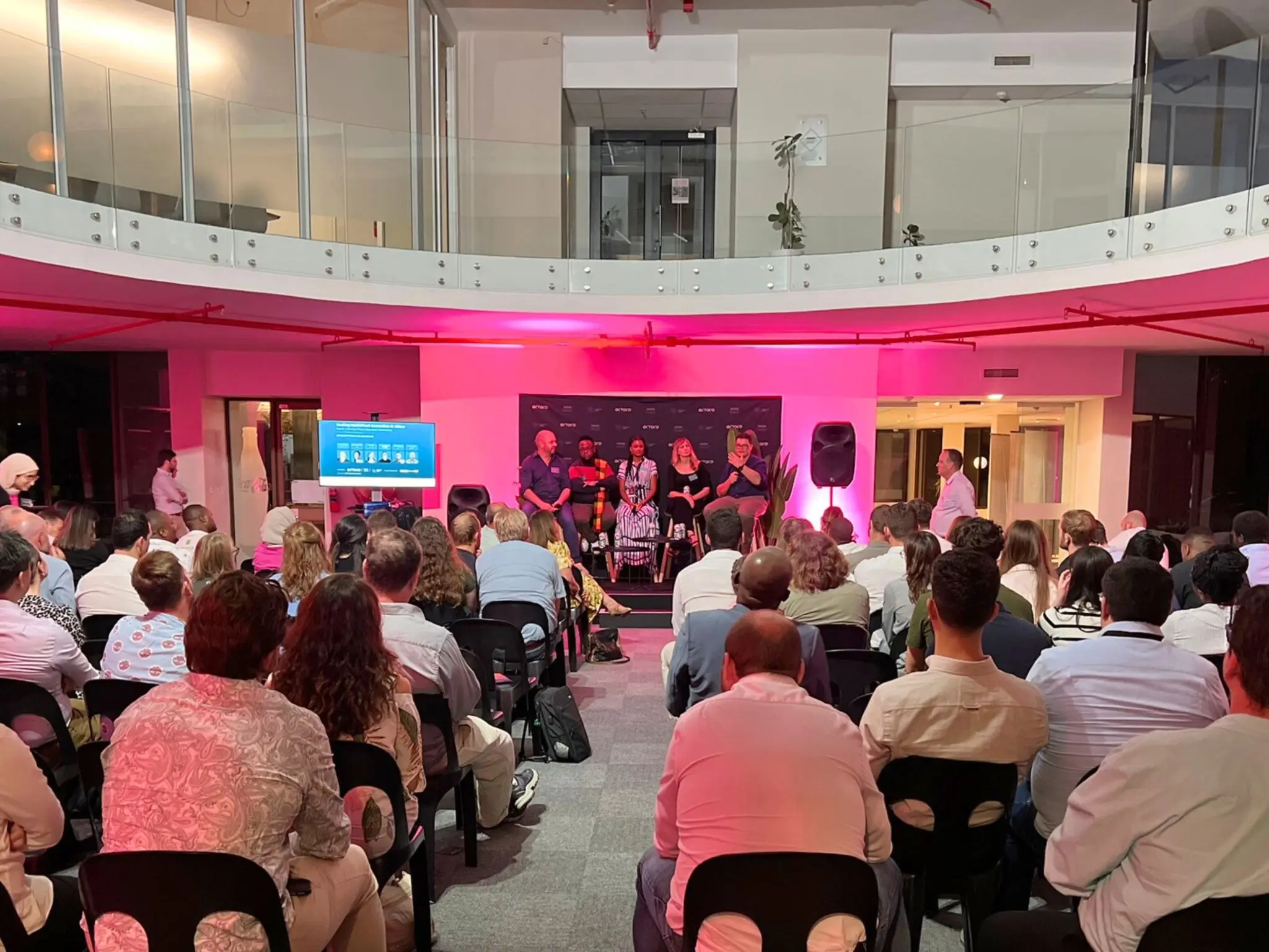 A panel of five speakers under pink stage lighting at the Scaling HealthTech Innovation in Africa event in Stellenbosch, with an audience seated in front of them